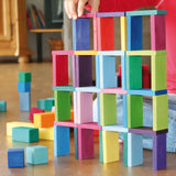 Child's hand stacking pieces from the Grimm's colour charts rally wooden toy set.
