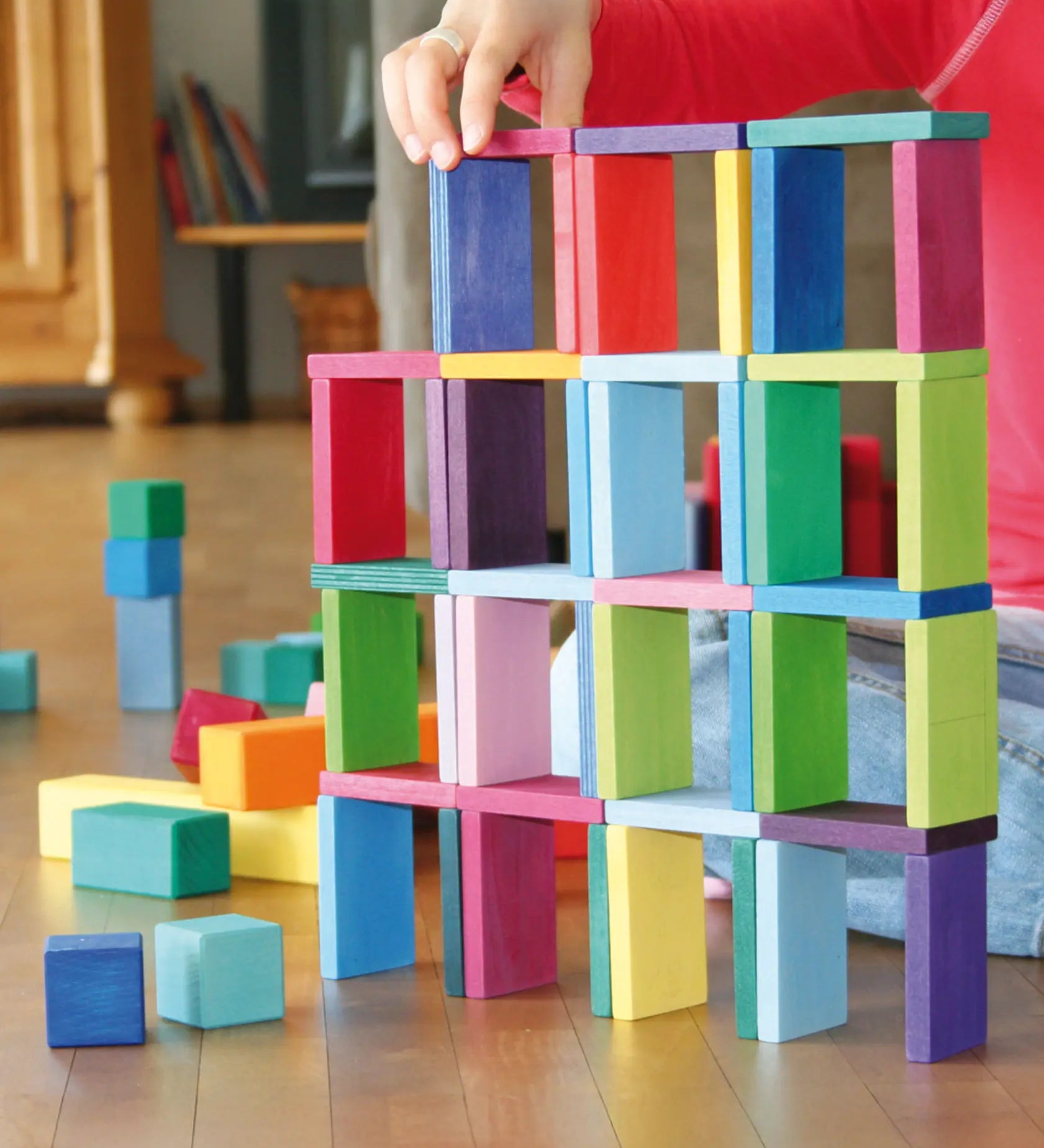 Child's hand stacking pieces from the Grimm's colour charts rally wooden toy set.