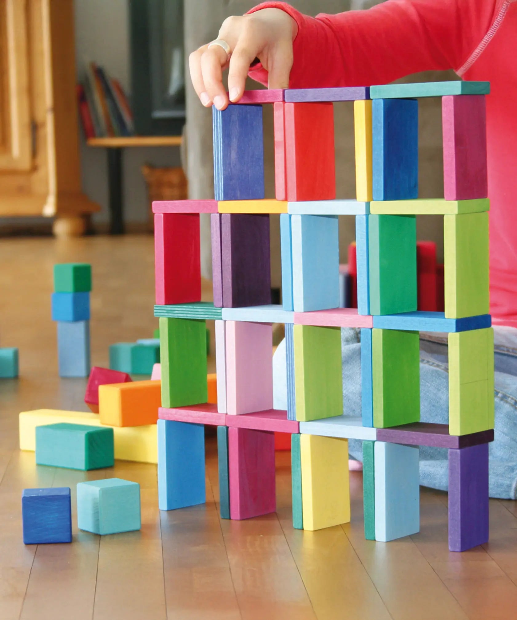 Child's hand stacking pieces from the Grimm's colour charts rally wooden toy set.