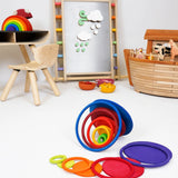 Rings and disks from the Grimms concentric set on a playroom floor with other wooden toys in the background