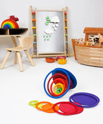 Rings and disks from the Grimms concentric set on a playroom floor with other wooden toys in the background