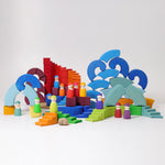 The pieces from the Grimm's Counter-Rotating Stepped Spiral wooden block set set up in a small world play scene with the Grimm's rainbow Friends. 