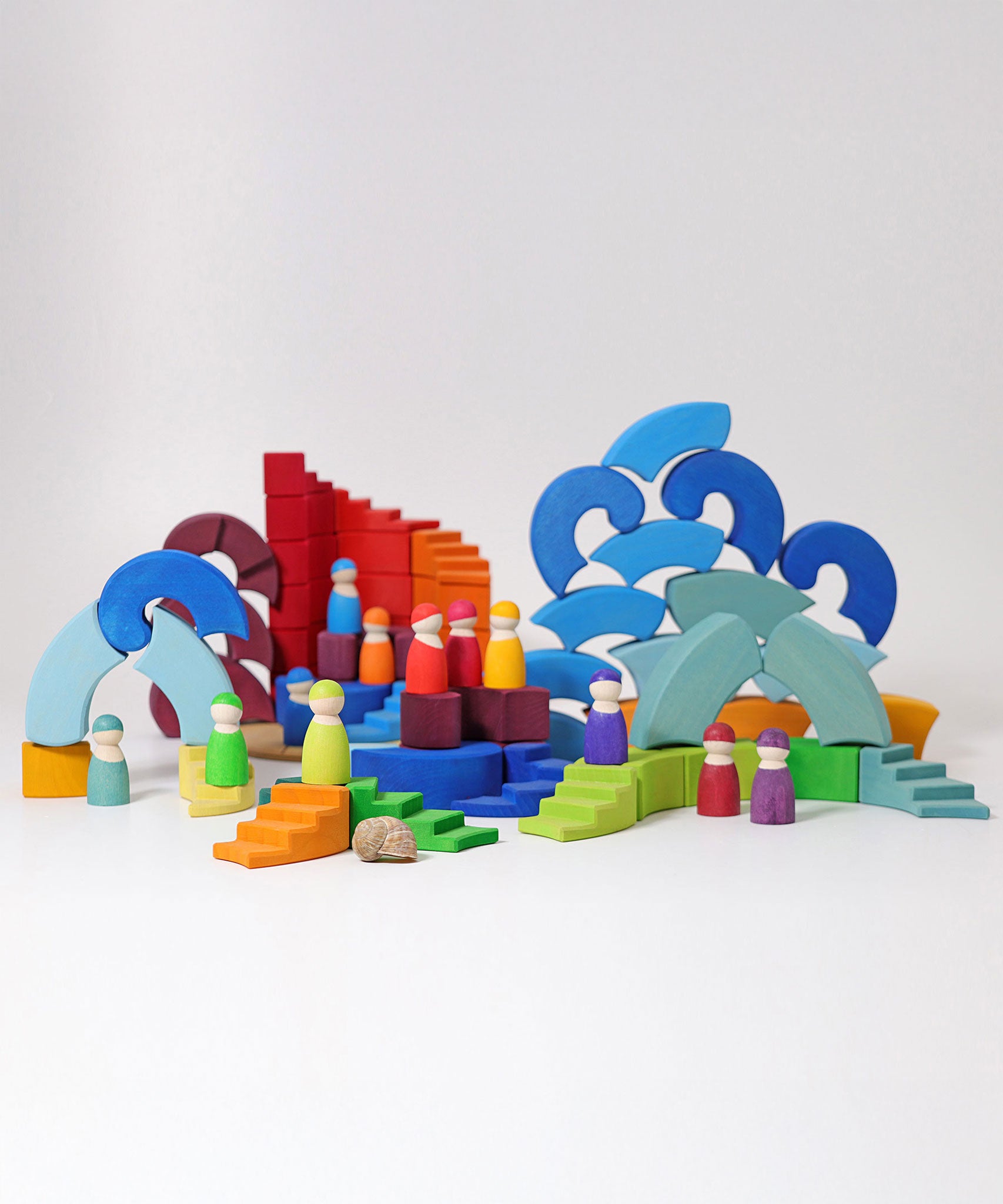 The pieces from the Grimm's Counter-Rotating Stepped Spiral wooden block set set up in a small world play scene with the Grimm's rainbow Friends. 