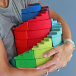 A person holding the Grimm's Counter-Rotating Stepped Spiral wooden block set in their arms.