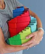A person holding the Grimm's Counter-Rotating Stepped Spiral wooden block set in their arms.