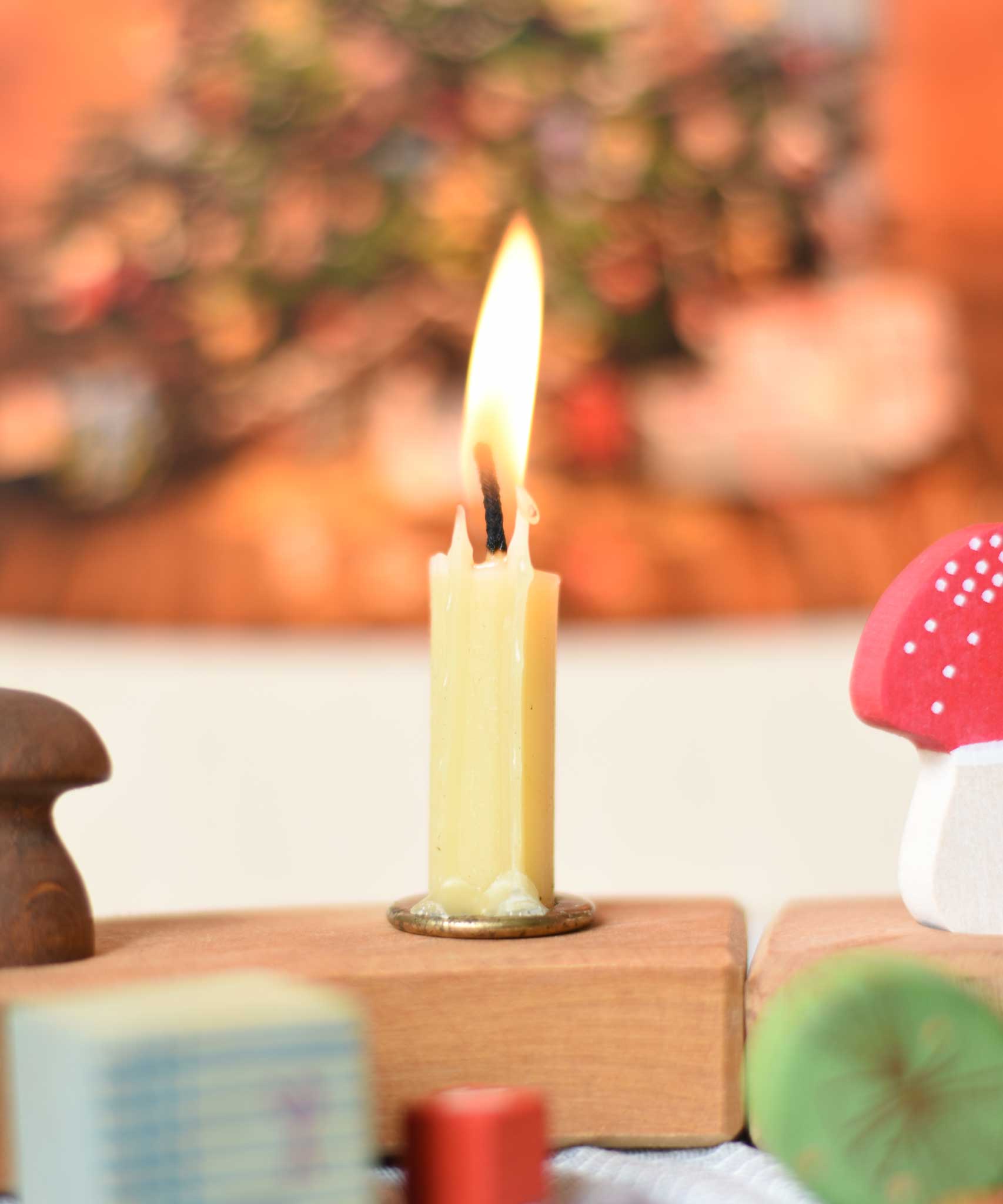 A cream coloured 100% beeswax candle from Grimm's designed to fit in the holders for the celebration rings. The candle has been lit 
