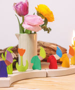 A row of Grimms decorative wooden dwarf figures with spring themed flowers on piece from the celebration ring