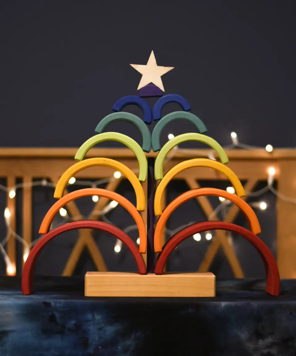 Grimm's Rainbow Stacking Tower stacked on the base in the shape of a tree with a wooden star placed on top.
