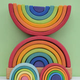 Grimm's Rainbow Stacking Tower with a rainbow and pastel mini rainbow placed in front of it. 