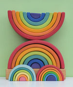 Grimm's Rainbow Stacking Tower with a rainbow and pastel mini rainbow placed in front of it. 