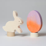 A Grimm's Easter Decorative Figure Set. the set includes a white bunny rabbit figure and a Batik Orange and purple coloured egg. 