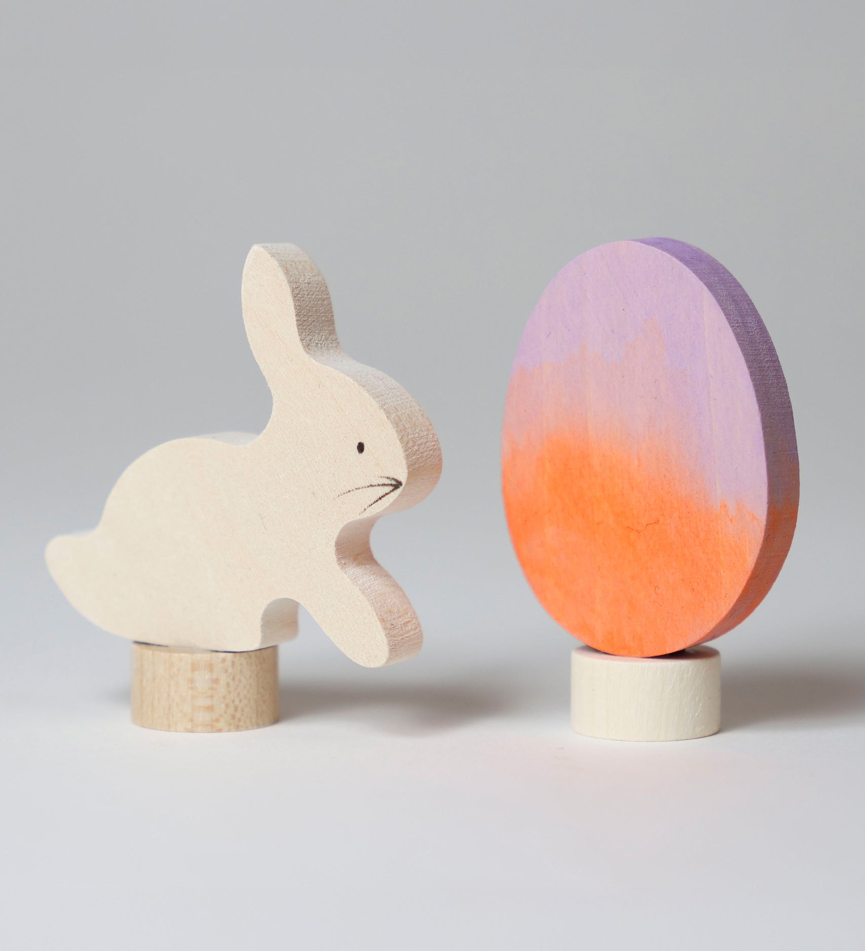 A Grimm's Easter Decorative Figure Set. the set includes a white bunny rabbit figure and a Batik Orange and purple coloured egg. 