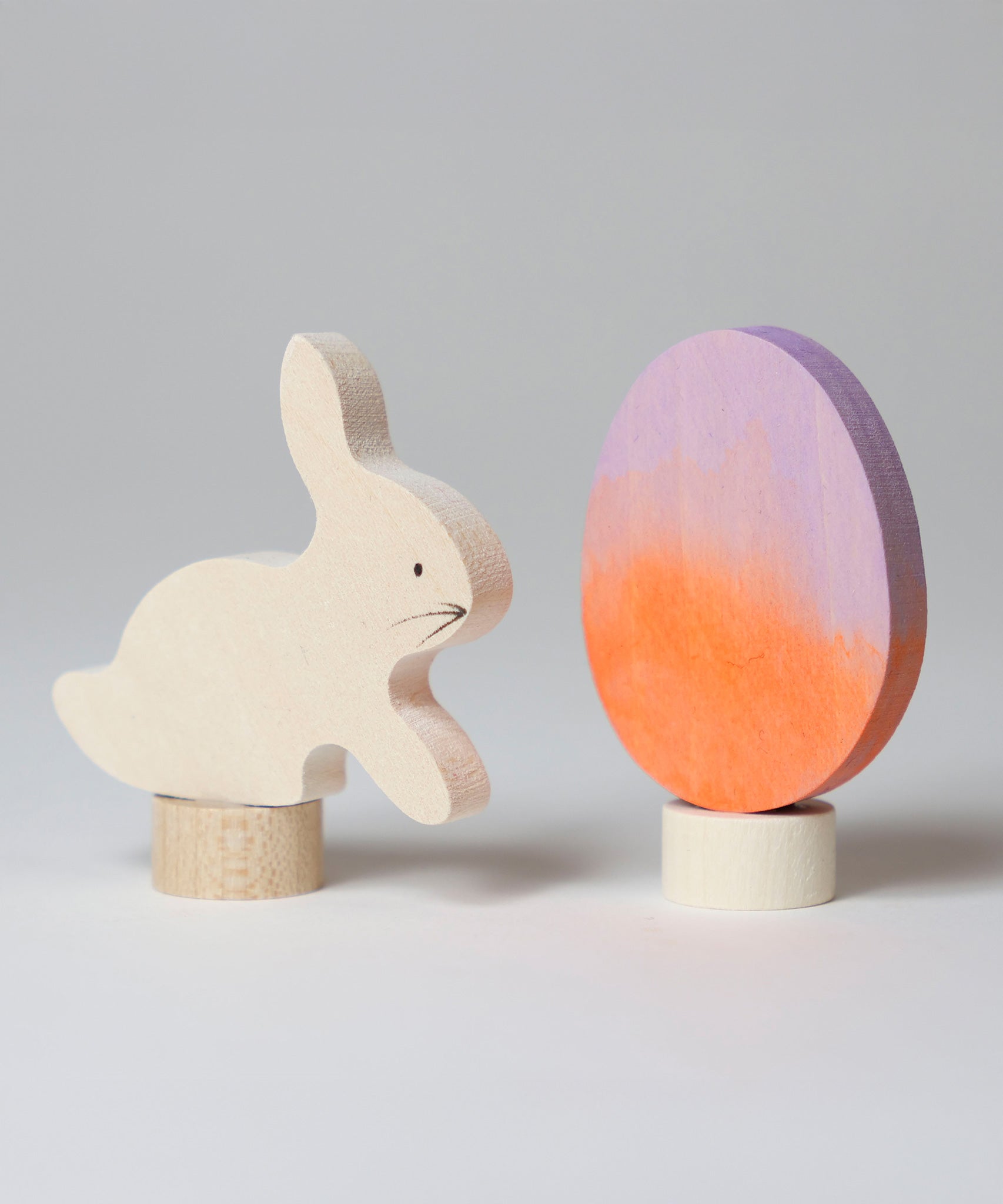 A Grimm's Easter Decorative Figure Set. the set includes a white bunny rabbit figure and a Batik Orange and purple coloured egg. 