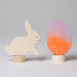 A Grimm's Easter Decorative Figure Set. the set includes a white bunny rabbit figure and a Batik Orange and purple coloured egg. 