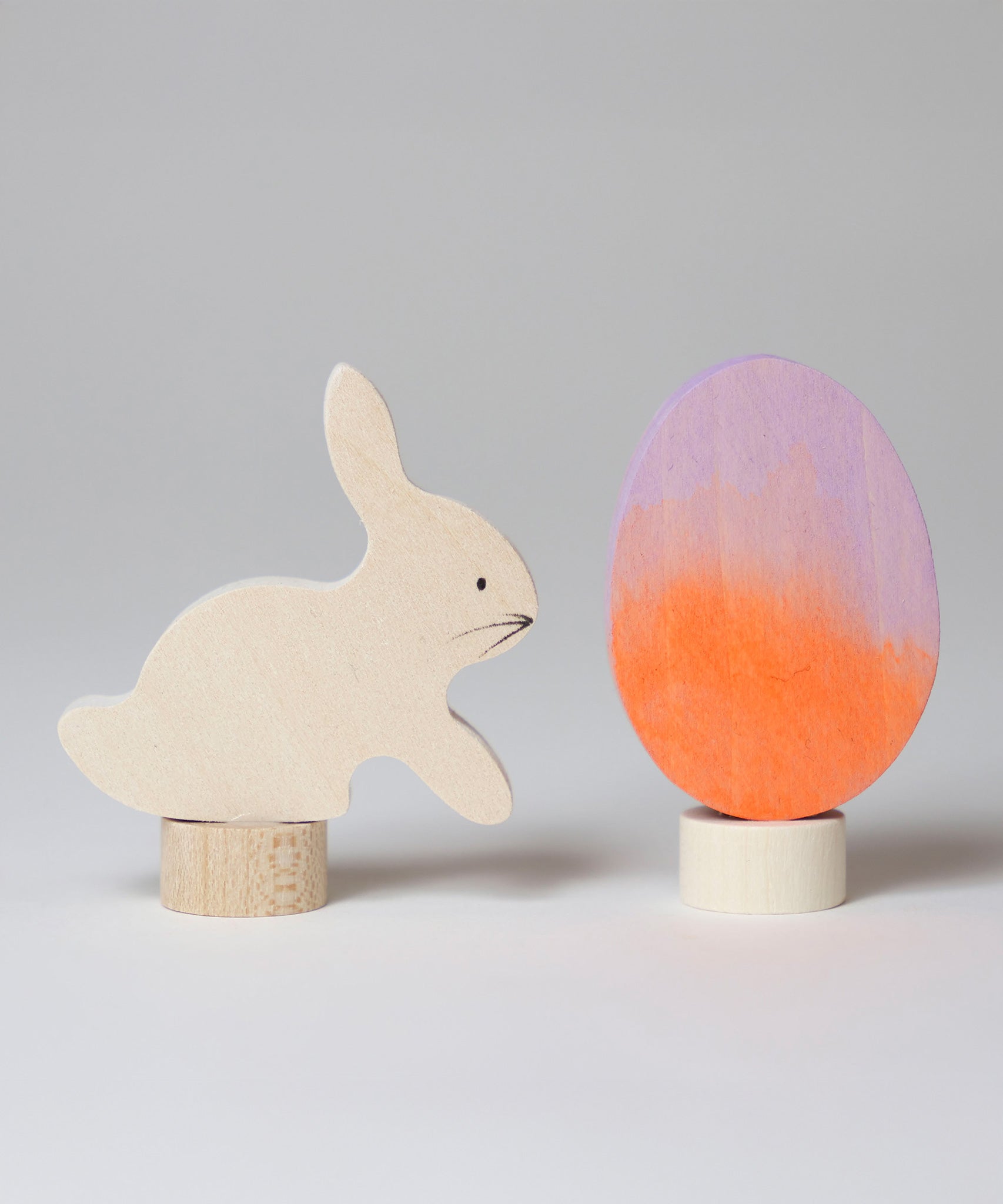 A Grimm's Easter Decorative Figure Set. the set includes a white bunny rabbit figure and a Batik Orange and purple coloured egg. 