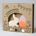 A Grimm's Easter Decorative Figure Set. the set includes a white bunny rabbit figure and a Batik Orange and purple coloured egg. The figures are shown in their cardboard packaging sleeve. 