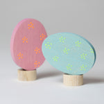 Grimm's Floral Duo Easter Eggs Decorative Figure Set. One egg is blue with light green dotted flower details and is side laying on it's base.  The other egg is pink with orange dotted flower details and is upright on it's base.