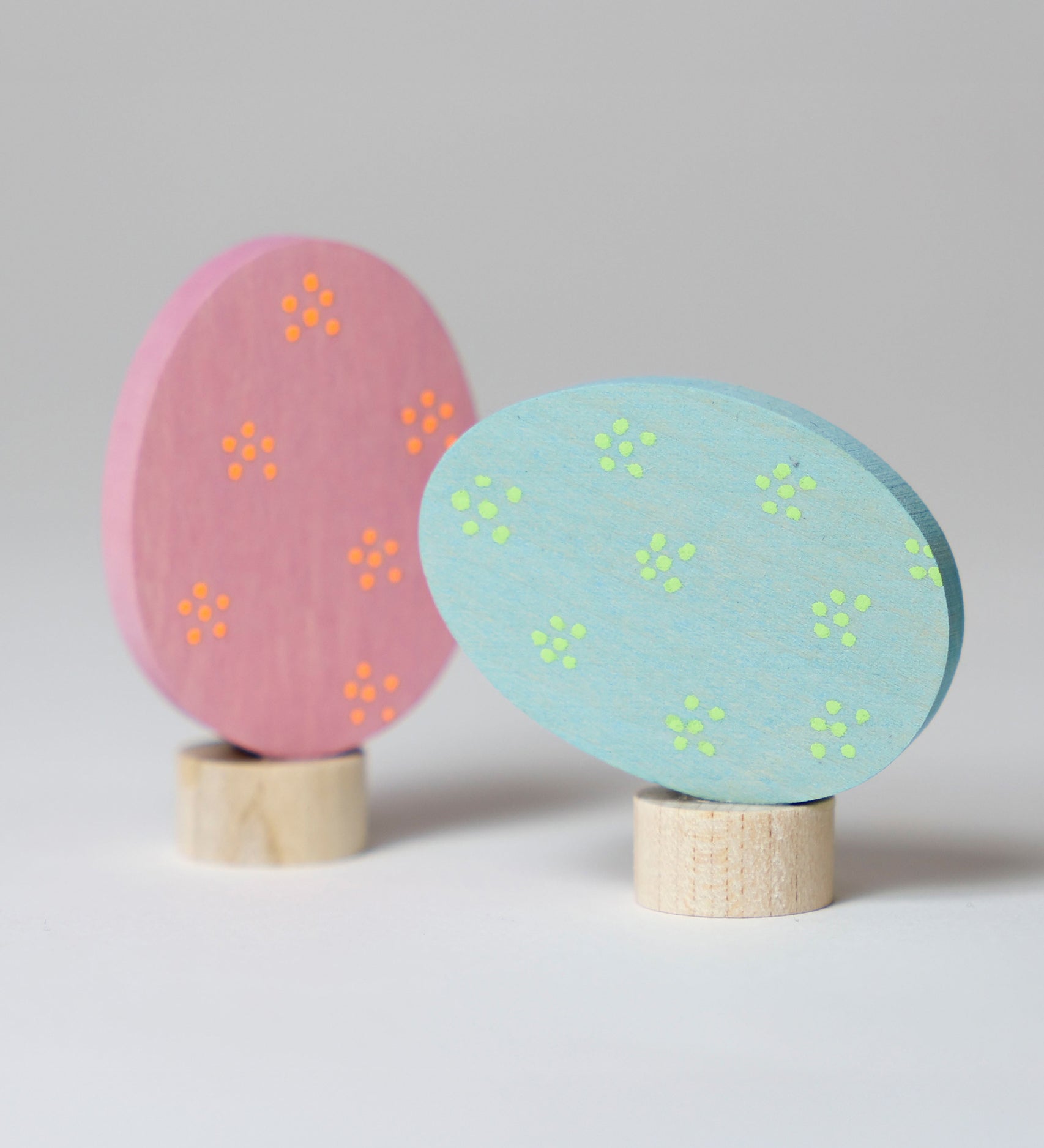 Grimm's Floral Duo Easter Eggs Decorative Figure Set. One egg is blue with light green dotted flower details and is side laying on it's base.  The other egg is pink with orange dotted flower details and is upright on it's base.