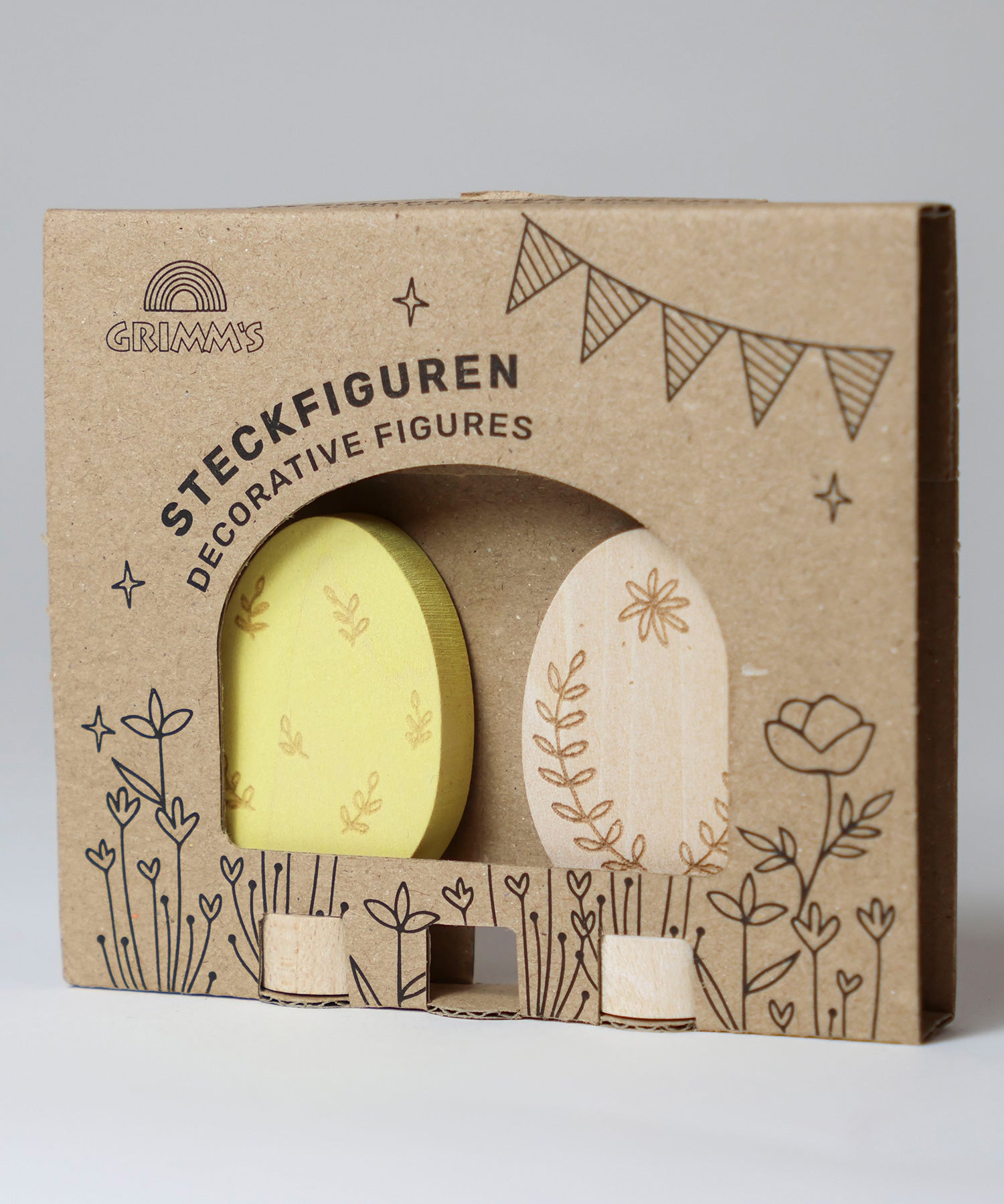 Grimm's Ornamental Duo Easter Eggs Decorative Figure Set. One egg is left natural withe floral themed outline details, the other painted in a light yellow with leaf outline details. The eggs are shown in their cardboard packaging sleeve. 