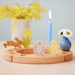 Grimm's Ornamental Duo Easter Eggs Decorative Figure Set. The eggs are placed on a natural wooden Grimm's celebration ring. Other decorative figures and a blue coloured candle can be seen in the background. 