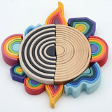 Grimms mini and large elements block laid in a circle with 6 piece rainbow with a larger 12 piece rainbow sets in the middle