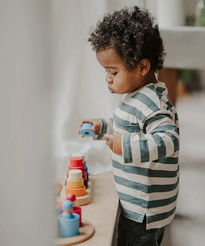 Child stacking a loose blue disk from the Grimms fabuto set