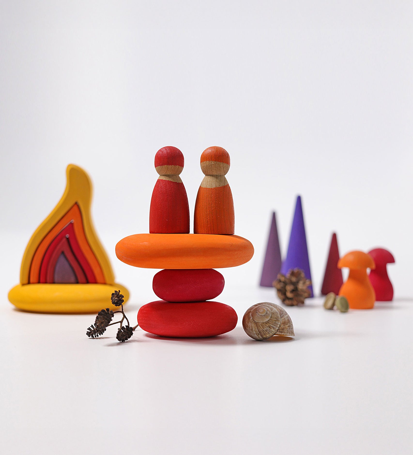 The Grimm's Fire Pebbles Building Set shown amongst a small world play set up alongside Grimm's friends, fire, forest and mushrooms. 
