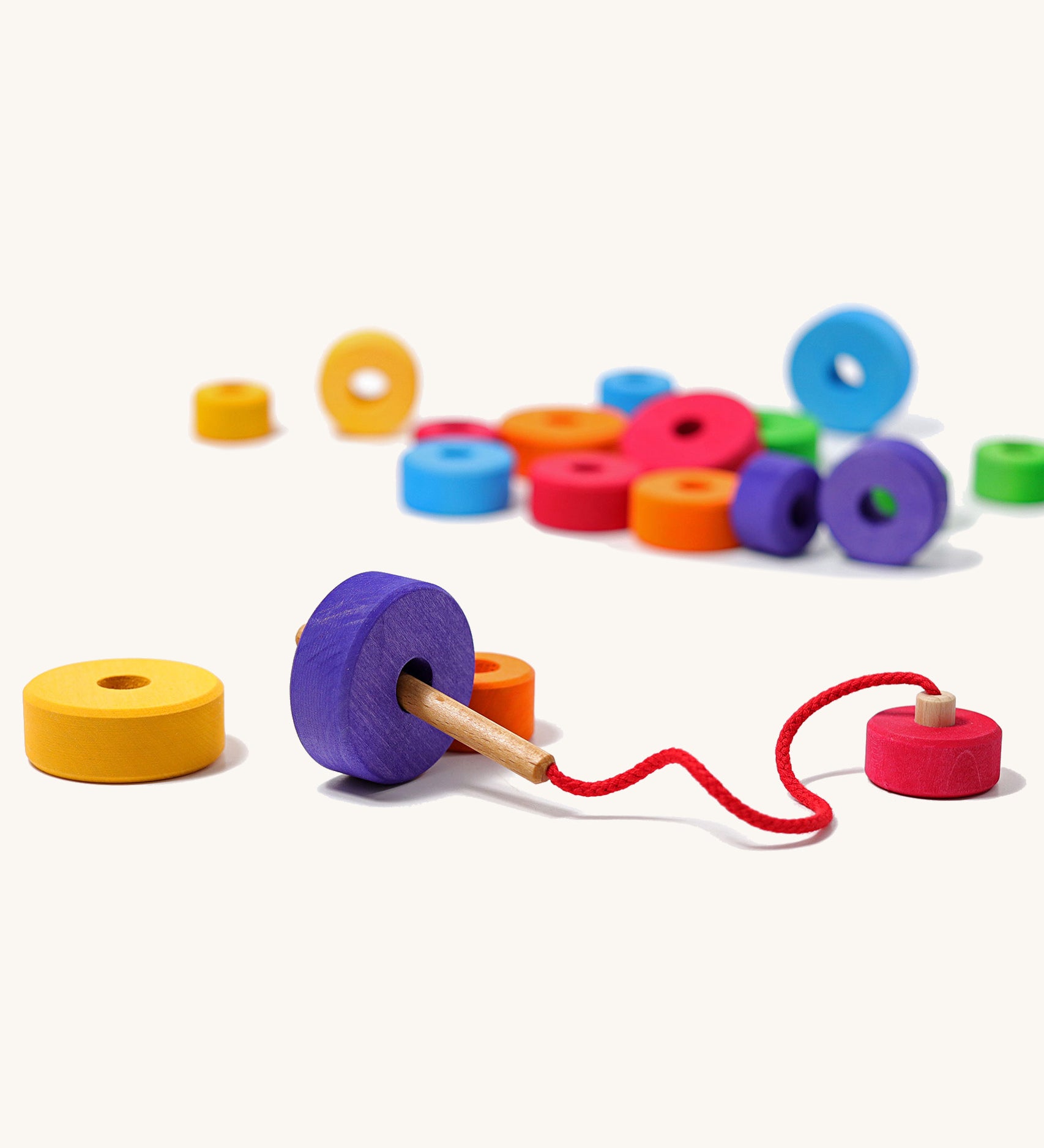 Grimms handmade and hand painted wooden first thread game available at Babipur. Features bright and chunky different sized disks with a hole in the middle for the wooden threading needle to string with