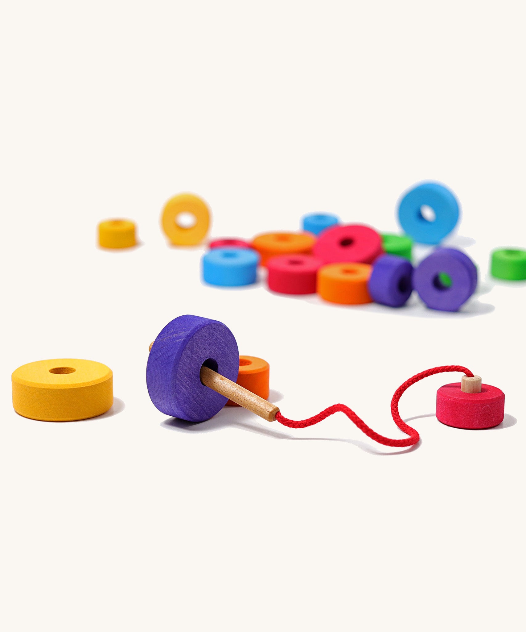 Grimms handmade and hand painted wooden first thread game available at Babipur. Features bright and chunky different sized disks with a hole in the middle for the wooden threading needle to string with