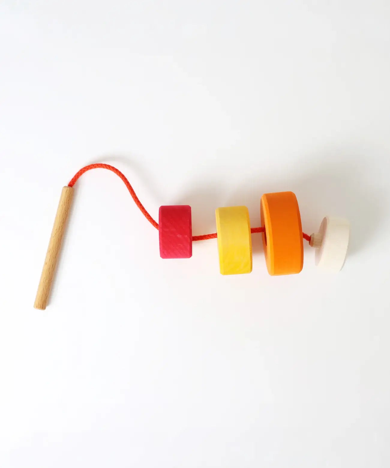 Grimms wooden threading needle with string fed through the bright and chunky disks 