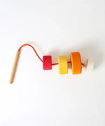 Grimms wooden threading needle with string fed through the bright and chunky disks 