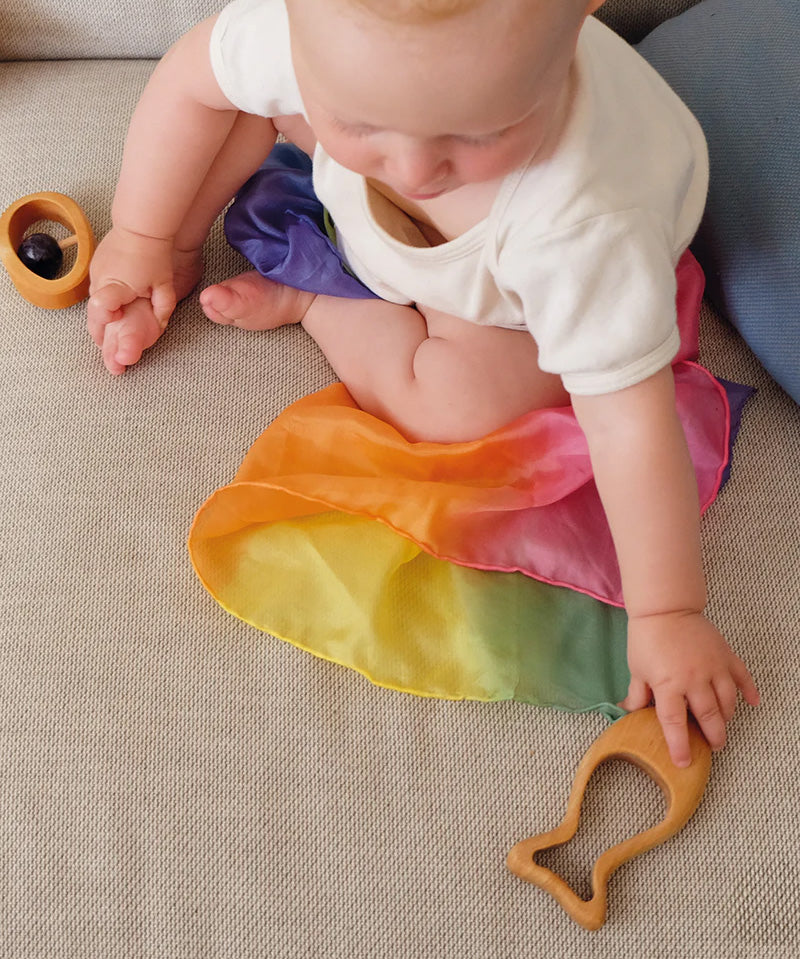 A baby reaching for the Grimm's Grasping Fish With Precious Stones.