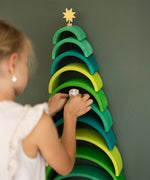 A close up of a child holding a toy candle and placing under a rainbow arch from the Grimms forest 12 piece set available at Babipur