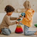Children stacking wooden blocks from the Grimms Geometric stacking tower set in a playroom