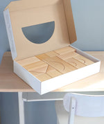 Grimm's giant natural wooden building blocks set in a cardboard box.