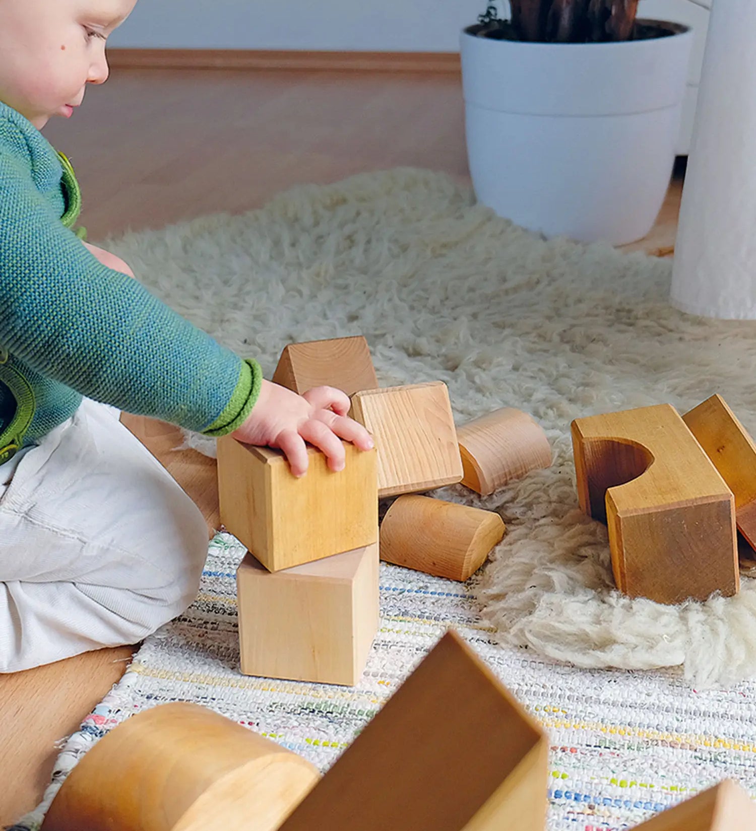 Child playing with Grimm's giant natural wooden building blocks set.