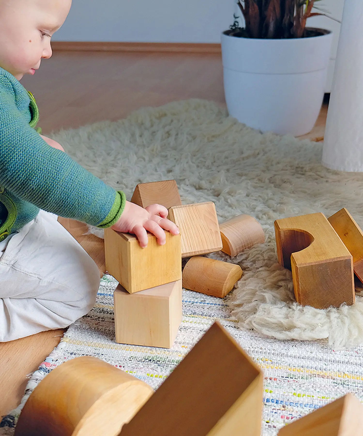 Child playing with Grimm's giant natural wooden building blocks set.