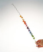 An adult holding one end of the giant Grimms spirelli available at Babipur. This  winding metal wire comes with coloured disks that make a noise when tipped over. 