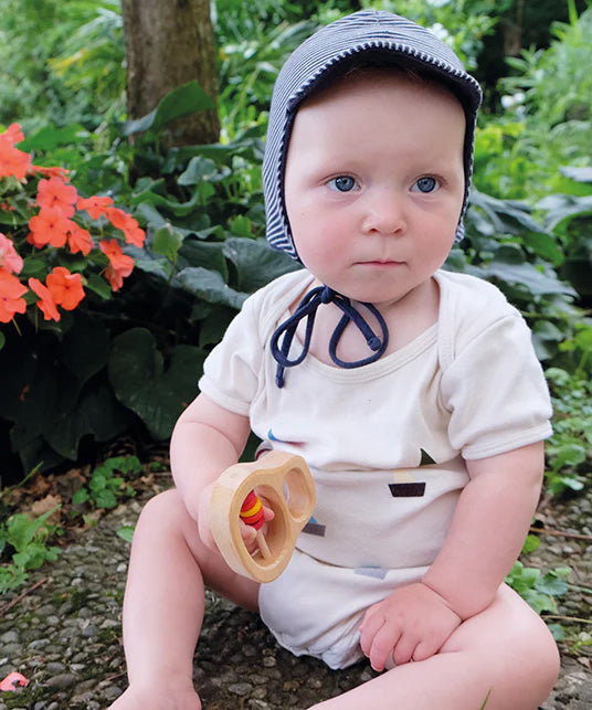 A baby holding the Grimm's Grasping Toy With 5 Rings.