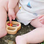 A close up of a baby pointing to the Grimm's Grasping Toy With 5 Rings.