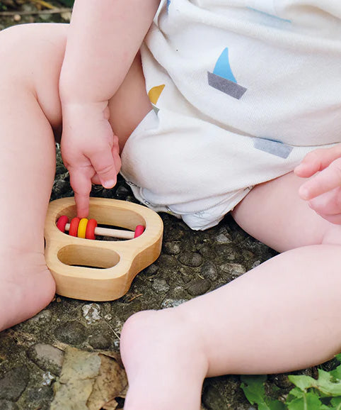 A close up of a baby pointing to the Grimm's Grasping Toy With 5 Rings.
