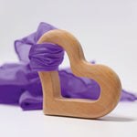 A piece of purple material tied to the Grimm's Grasping Toy Smooth Heart.