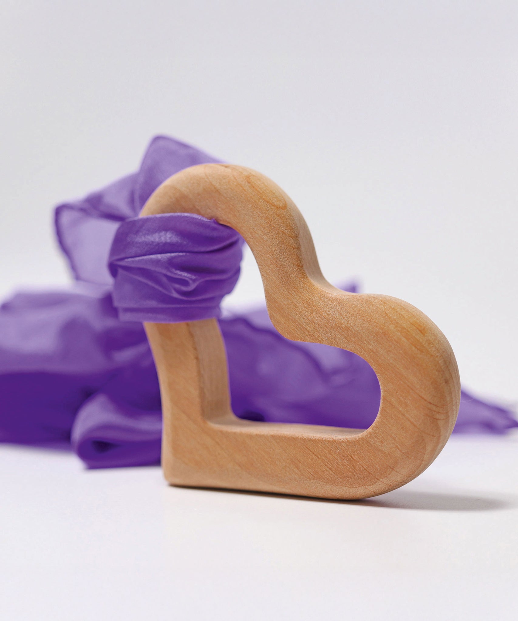 A piece of purple material tied to the Grimm's Grasping Toy Smooth Heart.
