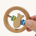 The Grimm's baby Grasping Toy Little Fish With Wooden Discs in an adult's hand.