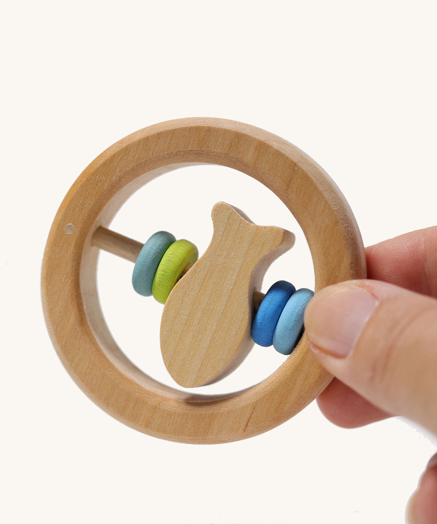 The Grimm's baby Grasping Toy Little Fish With Wooden Discs in an adult's hand.