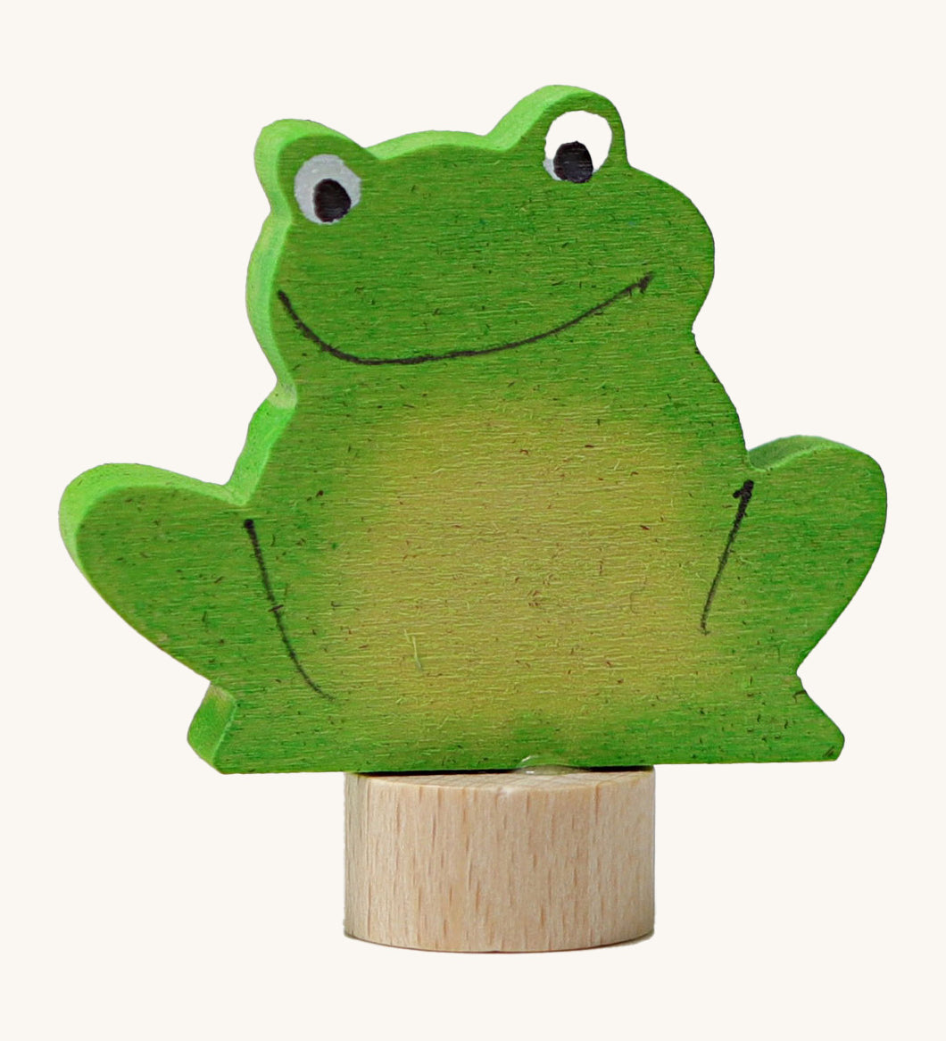 A Grimms green frog wooden decorative figure with playful features and a small base stand to slot into a decorative ring