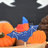 A close up of a Grimms bat decorative figure inserted in a Grimms wooden celebration ring with other Autumn decorative figures in the background available at Babipur.