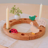 Grimm's wooden celebration ring with a ladybird, white vase, goose, signing bird and sheep decorative figures