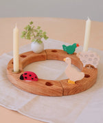 Grimm's wooden celebration ring with a ladybird, white vase, goose, signing bird and sheep decorative figures
