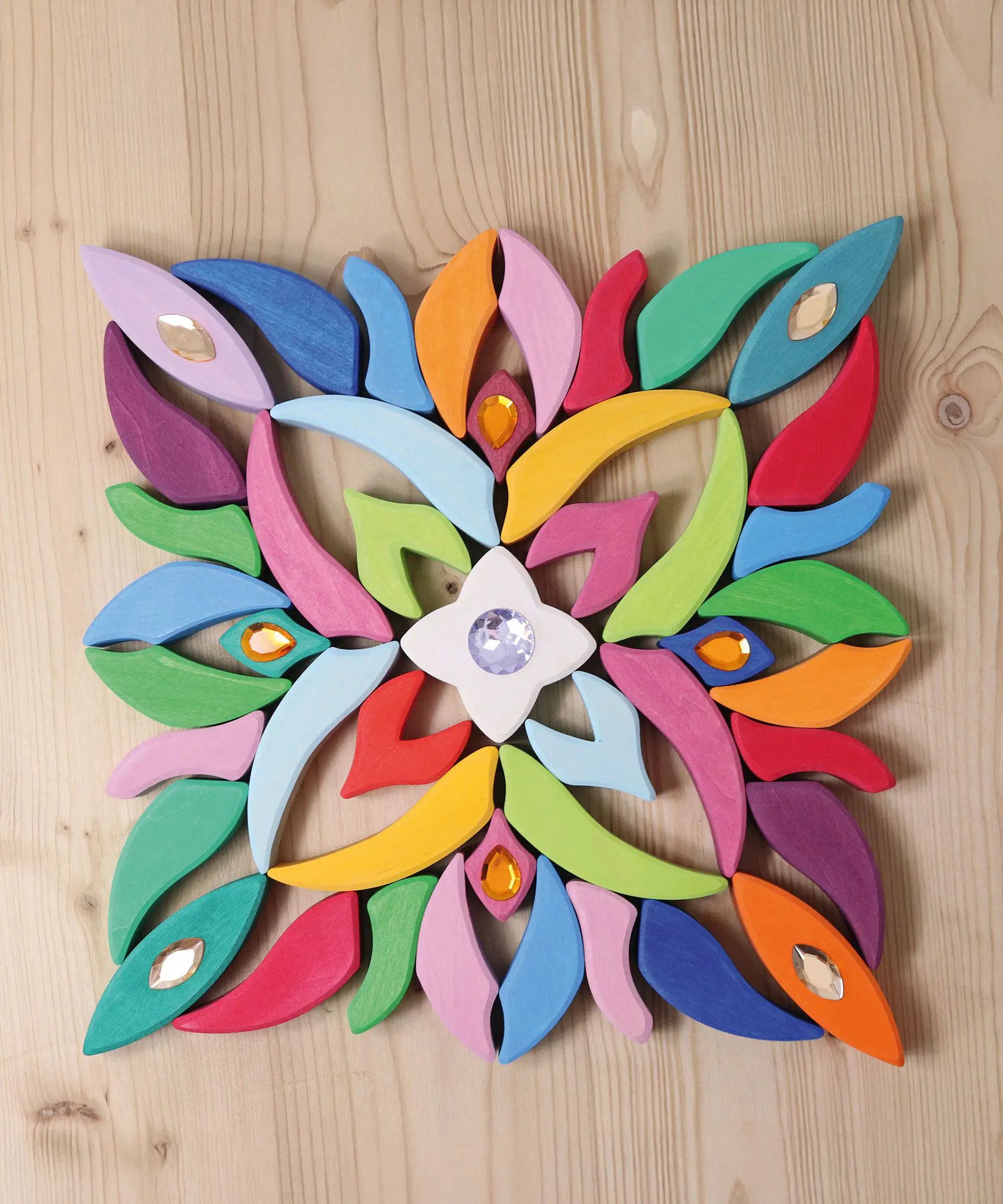 Grimm's Lara Mandala Building Set blocks used to create a square flatlay with little gems placed on top.